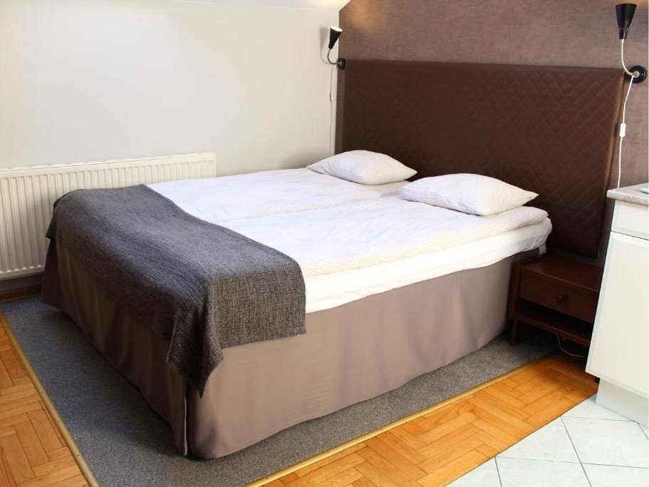 Pokój poddaszowy z dwoma pojedynczymi łóżkami, oknem dachowym, telewizorem na ścianie i drewnianą podłogą.