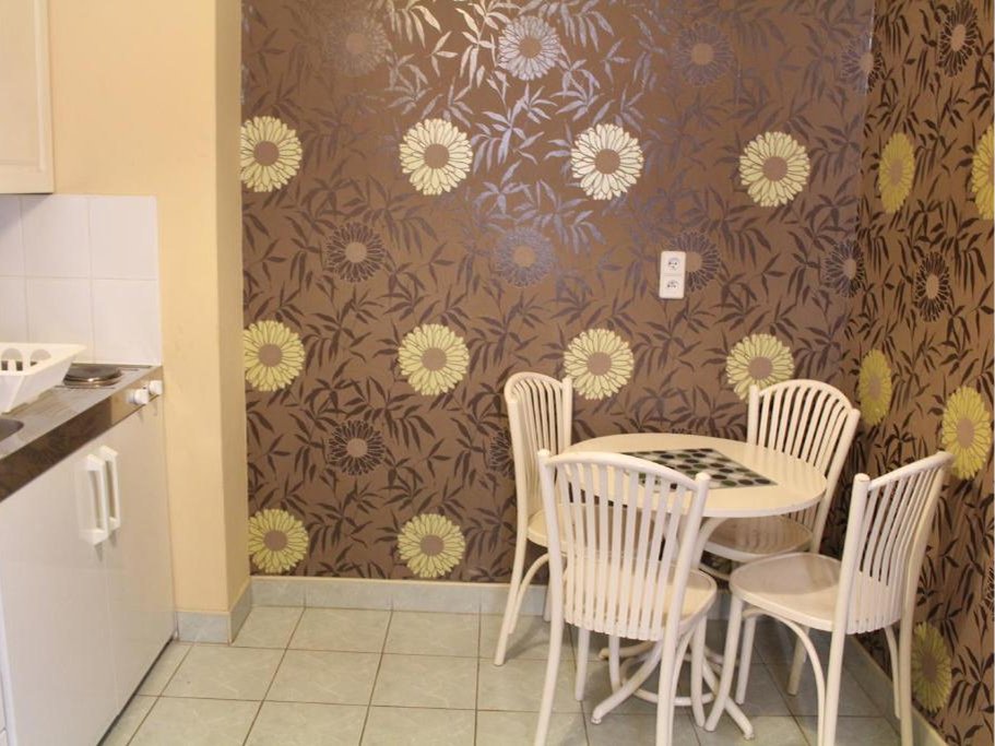 Pokój z pojedynczym łóżkiem i sofą, dwoma nocnymi stolikami, oknem z zasłonami oraz jasnymi ścianami i podłogą drewnianą.